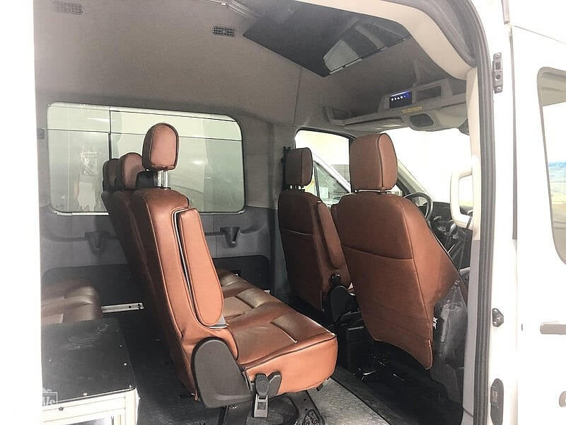 View inside an RV rental van. Features two rows of brown leather seats and large windows, perfect for touring.