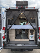 Explore this RV rental's spacious camper van interior! Features a bed, ample storage, and utility connections through open back doors.