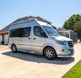 A silver Airstream Mercedes-Benz Sprinter RV rental van parked on a concrete driveway in bright sunlight.
