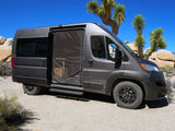 Dark gray rv rental campervan with open screened door, revealing interior, parked in a desert landscape with Joshua trees.