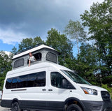 RV rental fun! A smiling person peeks from a white pop-top campervan. Perfect for camping and outdoor travel adventures.