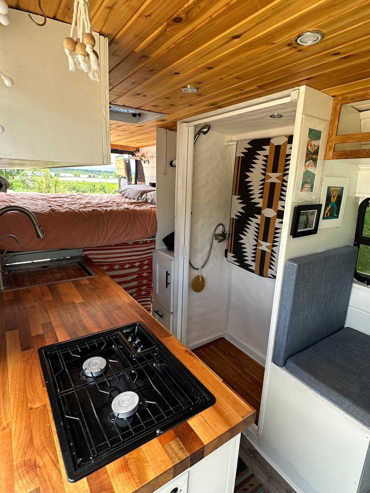 Cozy custom RV rental interior: kitchen, elevated bed, and shower for mobile adventures. — photo 6