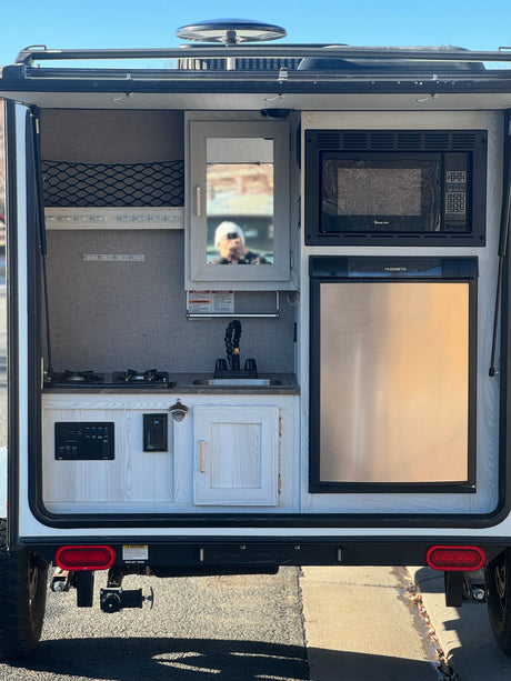 RV rental: Open rear outdoor kitchen with microwave, Dometic fridge, two-burner stove, sink, and controls.
