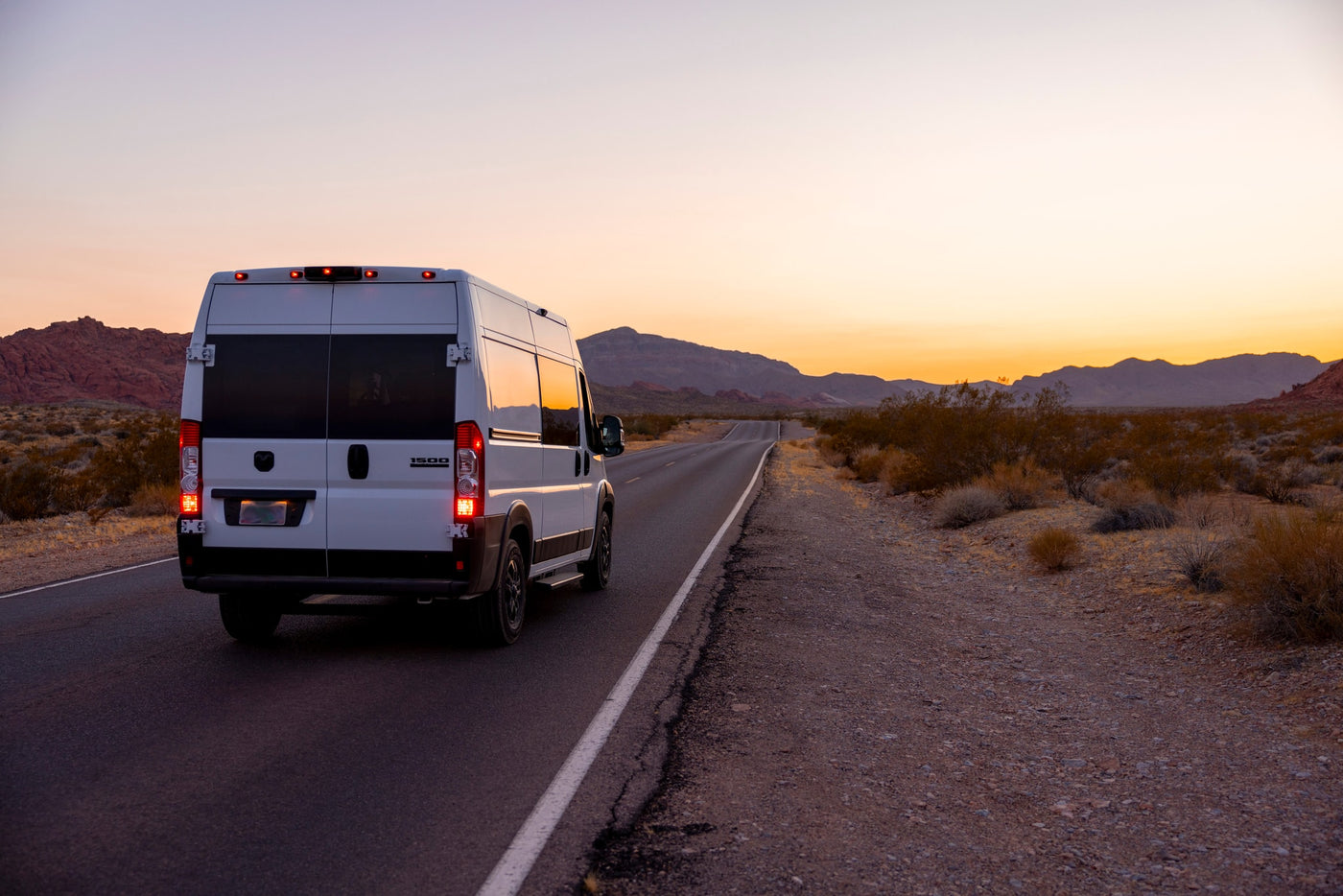 White RV rental van on a desert road at sunset, framed by mountains. Your ideal vehicle for scenic road trips & adventures. — photo 11