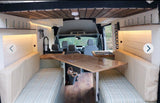 RV rental: Stylish van conversion interior with convertible dining/sleeping benches, a functional kitchenette, and wood accents.