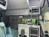 Step inside this RV rental: a modern kitchen, comfortable bed, and a ladder leading to a pop-top bunk for adventure.