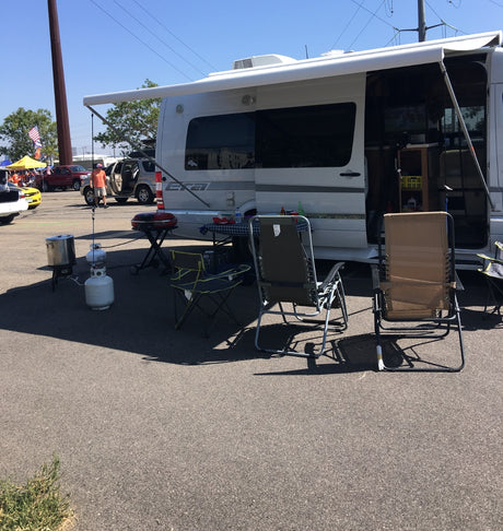 RV rental setup for a tailgate event with grill, chairs, and cooking gear. Perfect for outdoor leisure.