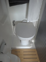 Compact RV rental bathroom features modern toilet, bidet sprayer, and shower curtain.
