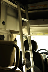 An RV rental's compact interior features a silver ladder for top bunk access, front seats, and overhead storage.