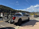 Silver F-150 Tremor truck with bikes, an outdoor alternative to RV rental, in a scenic mountain town.