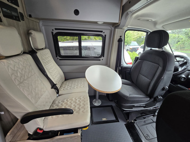 Spacious RV rental interior featuring comfy seats, a versatile table, and a clean, modern design for travel comfort. — photo 6