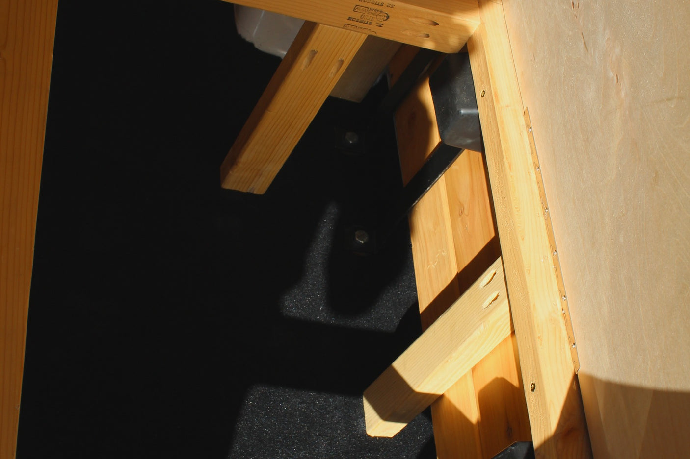 RV rental interior: sturdy wooden bed frame and structural elements secured by bolts to the dark floor.