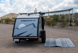 This FREESOLO teardrop RV rental, with an extended awning and mat, is ready for desert camping adventure.