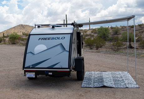 This FREESOLO teardrop RV rental, with an extended awning and mat, is ready for desert camping adventure.