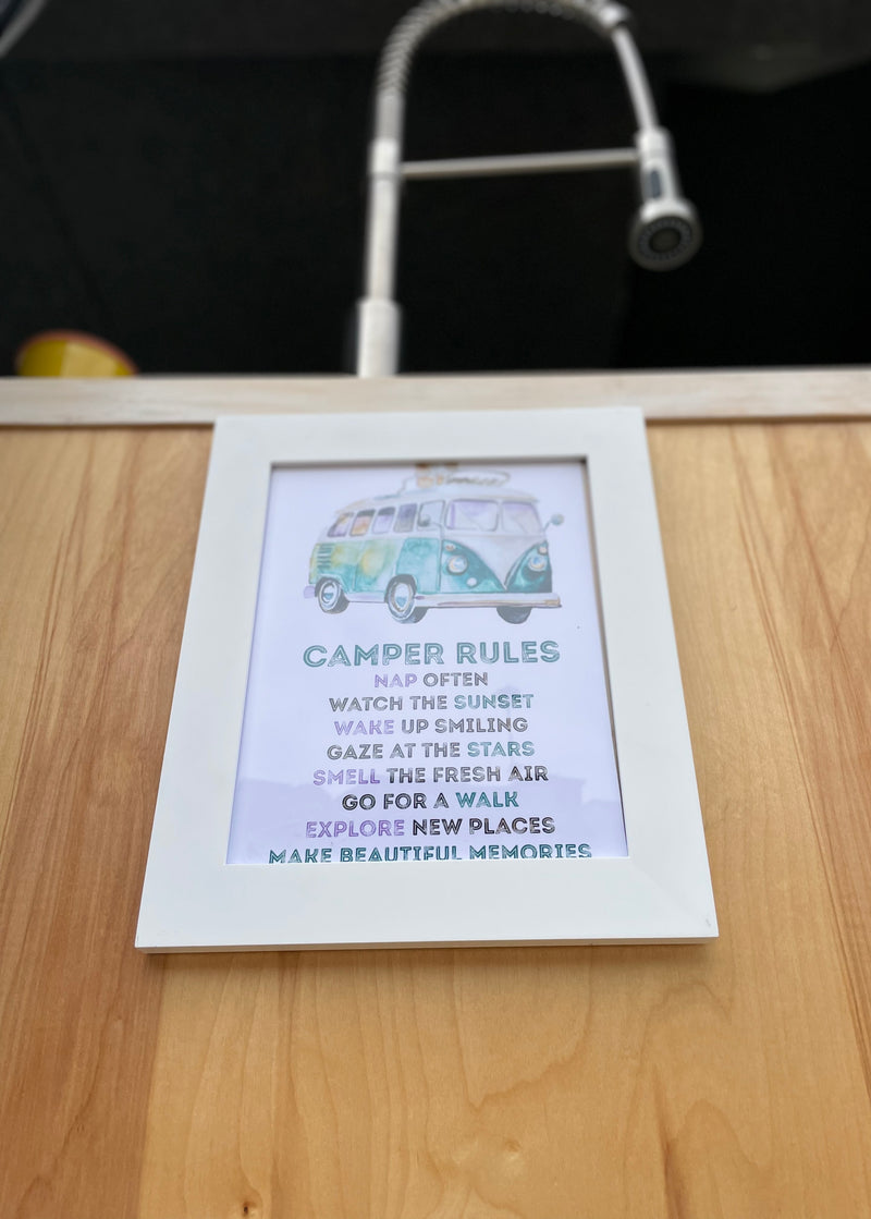 A "Camper Rules" sign, featuring a VW bus illustration and inspiring advice for enjoyable travels, displayed in an RV rental. — photo 11