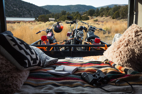 RV rental view: Three motorcycles loaded in back, with cozy pillows & binoculars, overlooking a scenic lake & mountains.