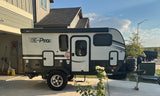 A Flagstaff E-Pro RV rental is parked with a Ford Bronco in a sunny driveway, ready for adventure.