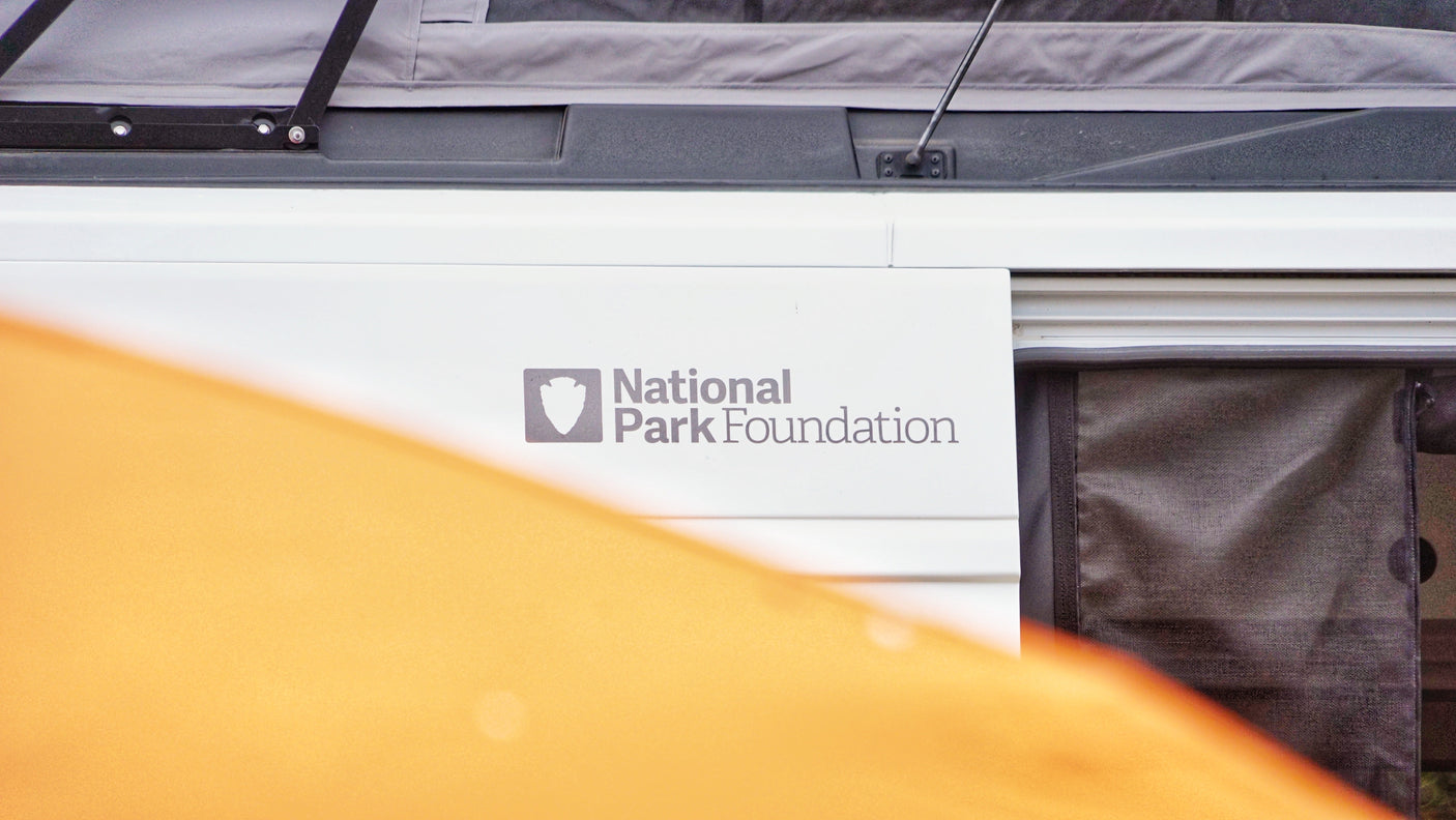 RV rental side with National Park Foundation logo, screen, and orange fabric partially obscuring the view.