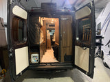 View into a well-appointed camper van's interior through its open rear doors, suitable for an RV rental adventure.