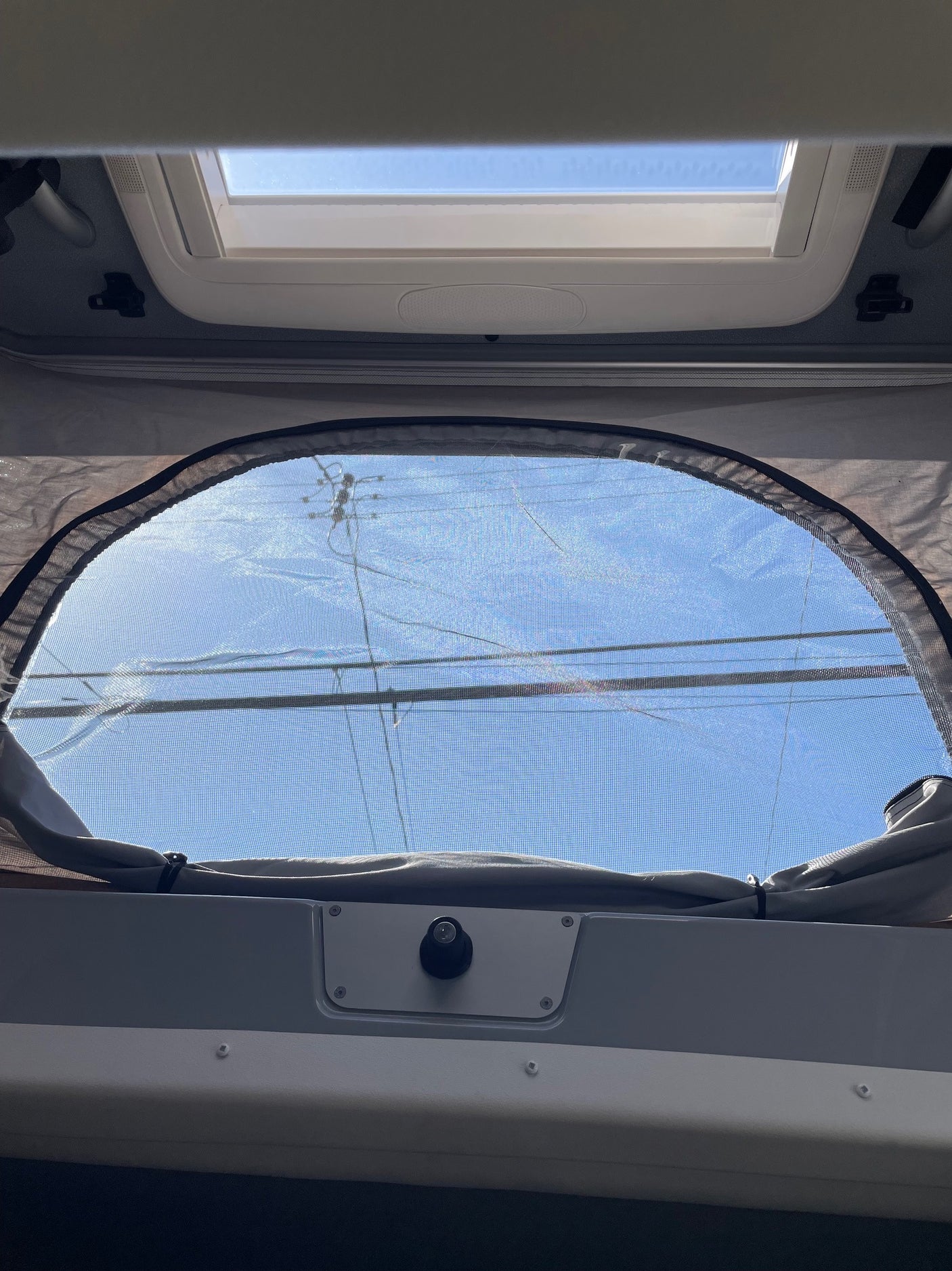 Inside an RV rental: Blue sky visible through the overhead skylight and screened pop-top window.