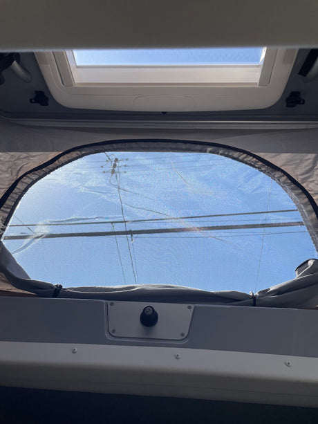 Inside an RV rental: Blue sky visible through the overhead skylight and screened pop-top window.