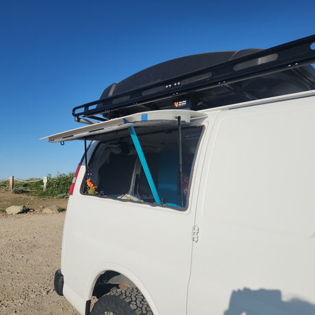 White camper van with open side window, roof rack & cargo box. Ready for your next rv rental journey!