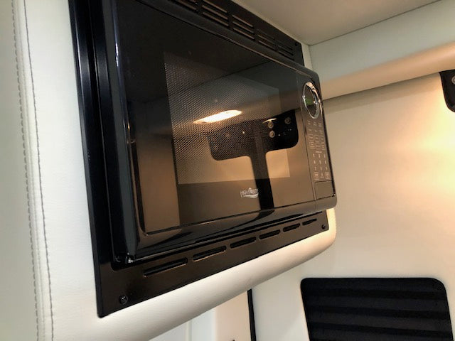 Brightly lit black microwave oven, seamlessly integrated into an RV rental's interior for your convenience. — photo 12
