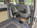 RV rental camper van interior showing rear seats, kitchenette, floor, and a mounted fire extinguisher for safety.