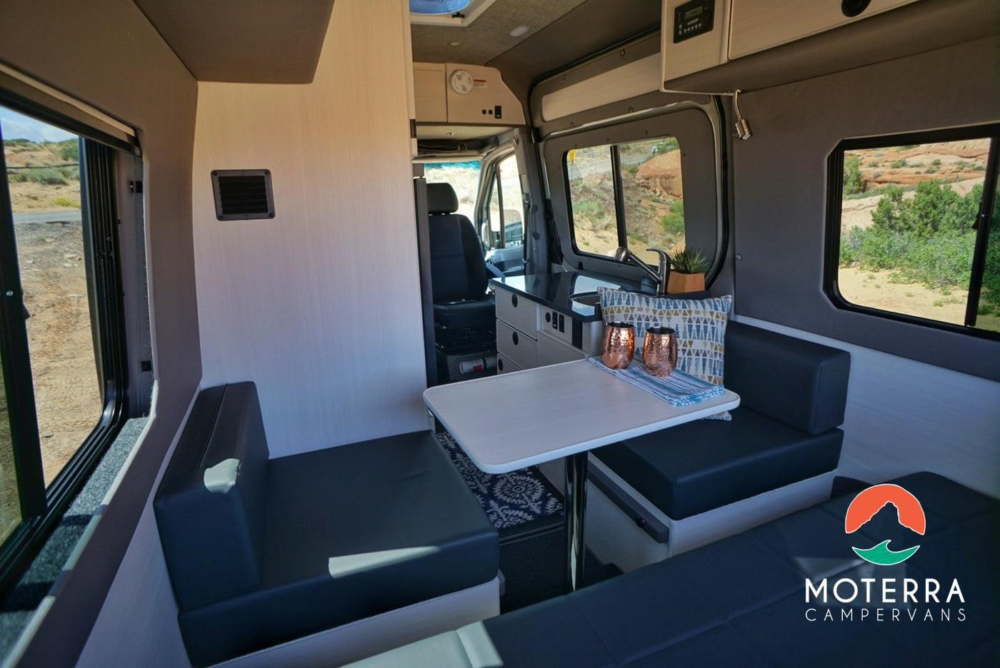 Modern campervan RV rental interior featuring a dinette, compact kitchen, comfy seating, and scenic views. — photo 2