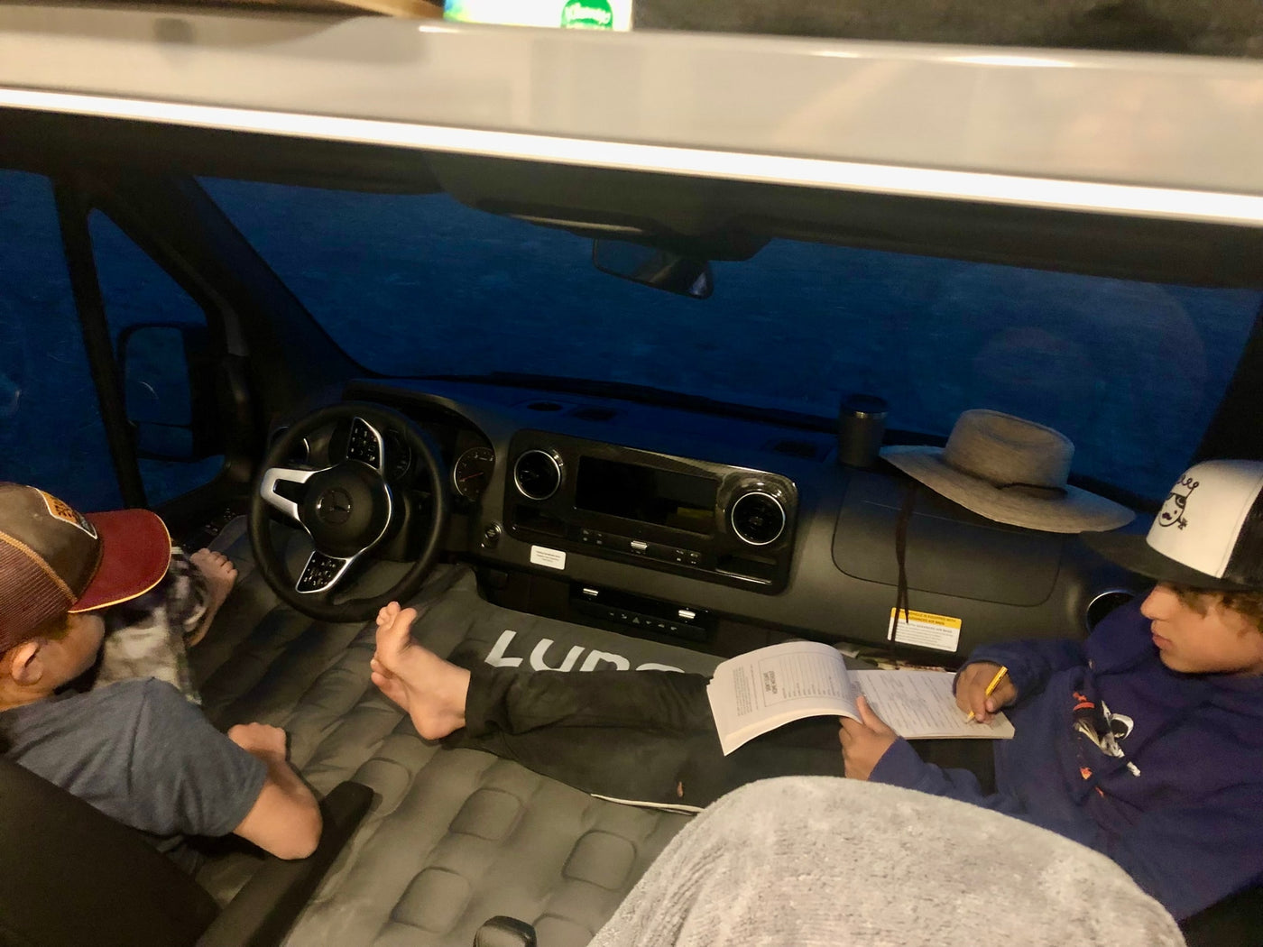 Cozy RV rental adventure: Kids relax in a camper van interior, one reading on their Luno air mattress. — photo 8