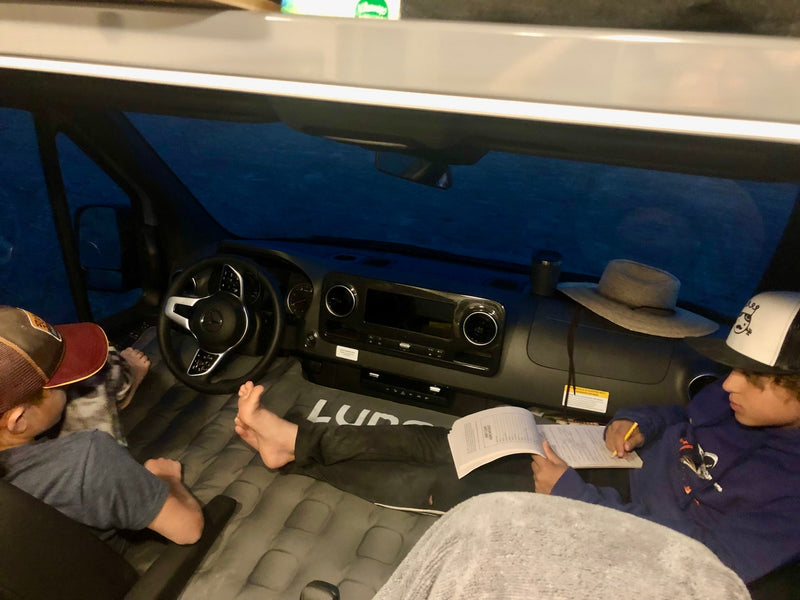 Cozy RV rental adventure: Kids relax in a camper van interior, one reading on their Luno air mattress. — photo 8