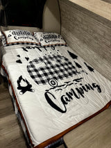 Camping-themed bedding with a plaid RV, trees, and campfire in a cozy RV rental.