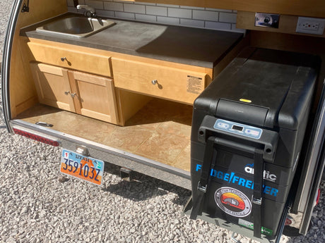 Rear galley of a Utah teardrop trailer RV rental with sink, cabinets, and pull-out fridge/freezer.
