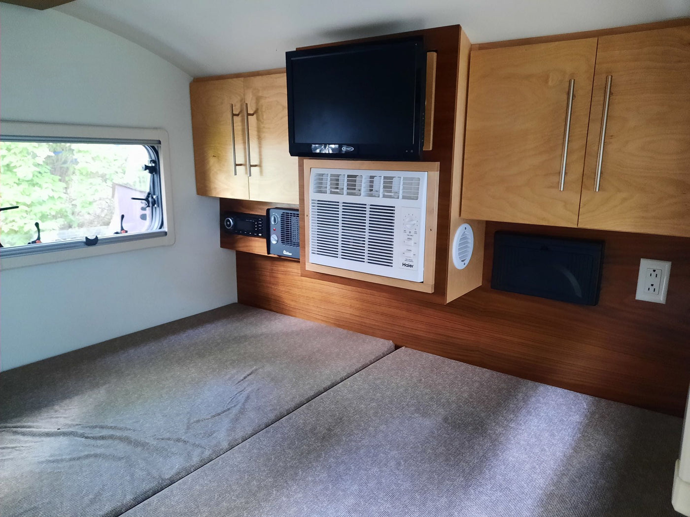 This RV rental interior features a bed, mounted TV, AC unit, and built-in storage. — photo 5