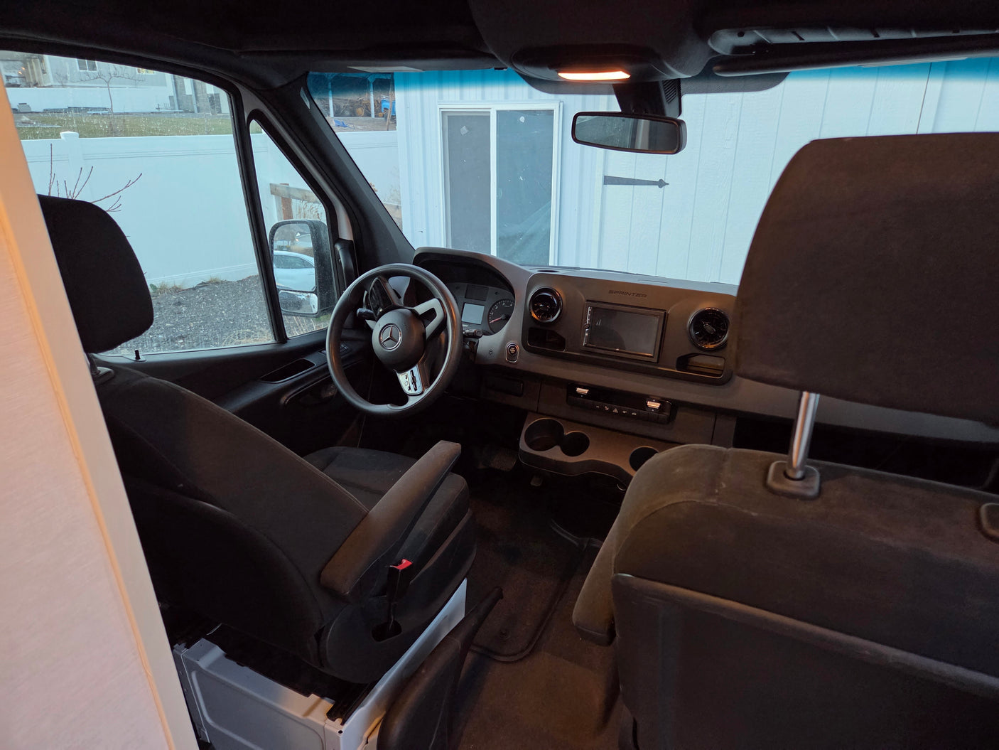 Front cabin of an RV rental Mercedes Sprinter van, with steering wheel, dashboard, and seats visible.