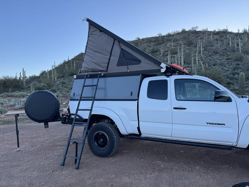 White Toyota Tacoma overland RV rental with a pop-top camper, ladder & spare tire, perfect for desert camping adventures. — photo 5