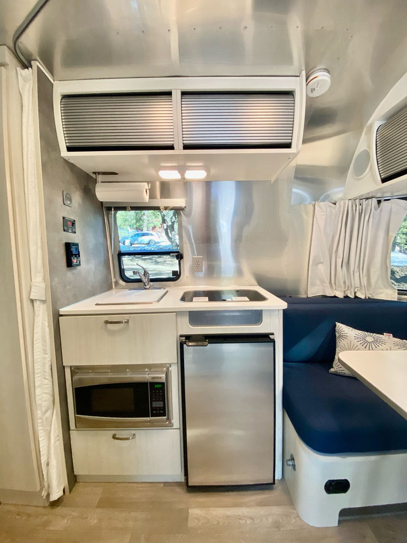  and large windows with outdoor views.|Cozy Airstream rv rental interior features a dinette — photo 7