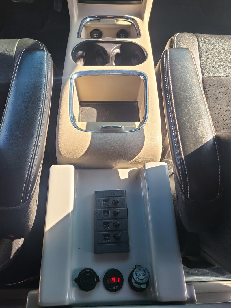 RV rental interior: A custom power panel with switches (fridge, lights, USB), voltmeter, and 12V outlets on the center console. — photo 7