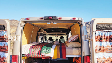 RV rental adventure! Open camper van doors reveal a comfy bed & scenic desert view. Perfect for van life exploration.