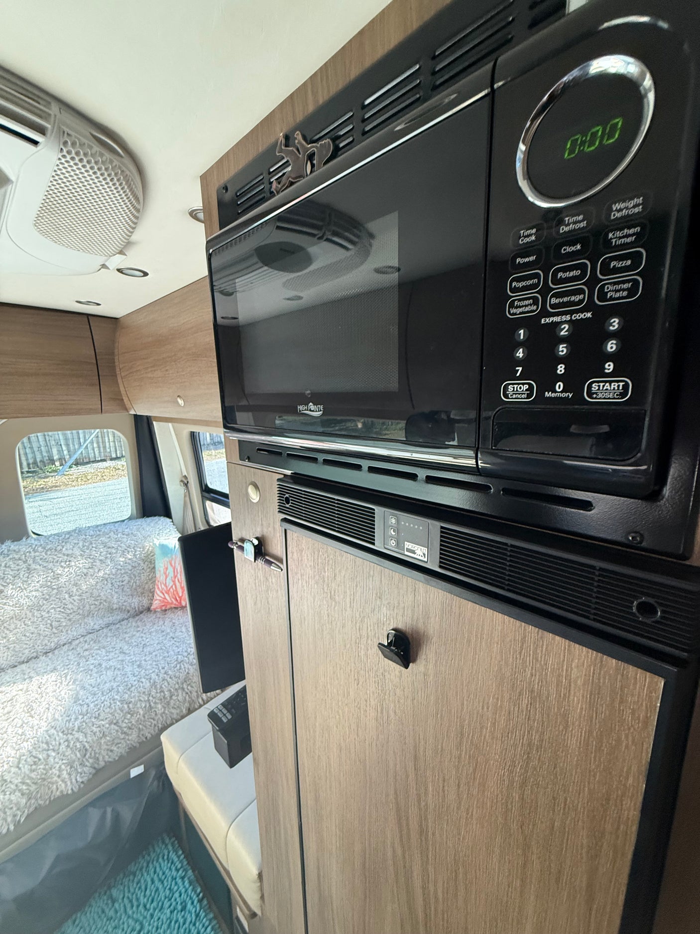 Explore this rv rental's interior: a modern kitchen with High Pointe microwave, Norcold fridge, and cozy living area.