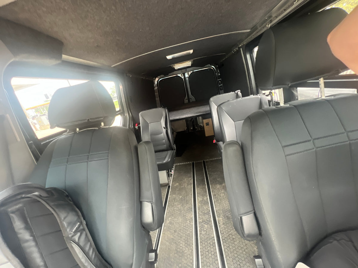 Step inside this RV rental: versatile seating, a raised bed, and floor tracks for your next adventure. — photo 5