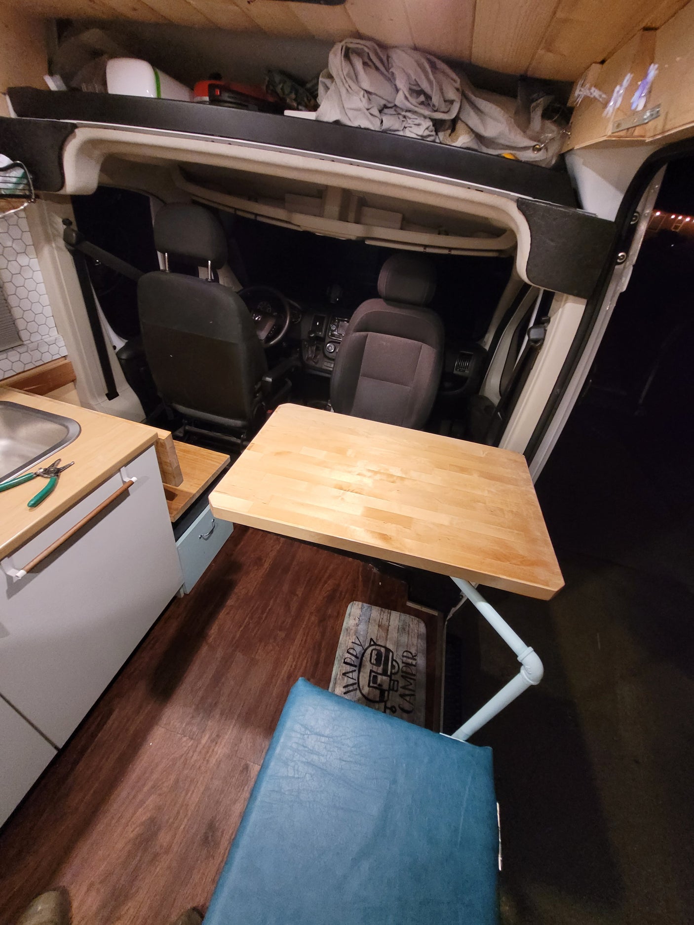 Inside an RV rental: a wood table/counter, sink, and front seats are visible, designed for compact van life.