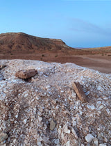 Explore vast desert vistas with an RV rental. Piles of light-colored rocks in the foreground, tiered red hills under a clear sky.
