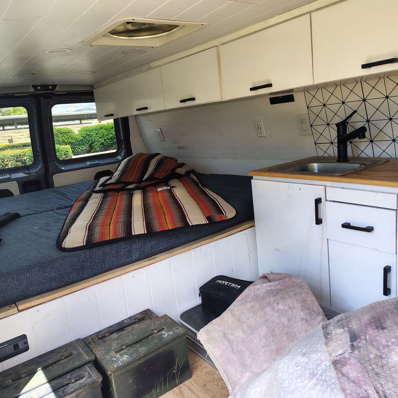 RV rental interior: cozy bed, small kitchen, overhead cabinets, and storage for mobile living adventures. — photo 5