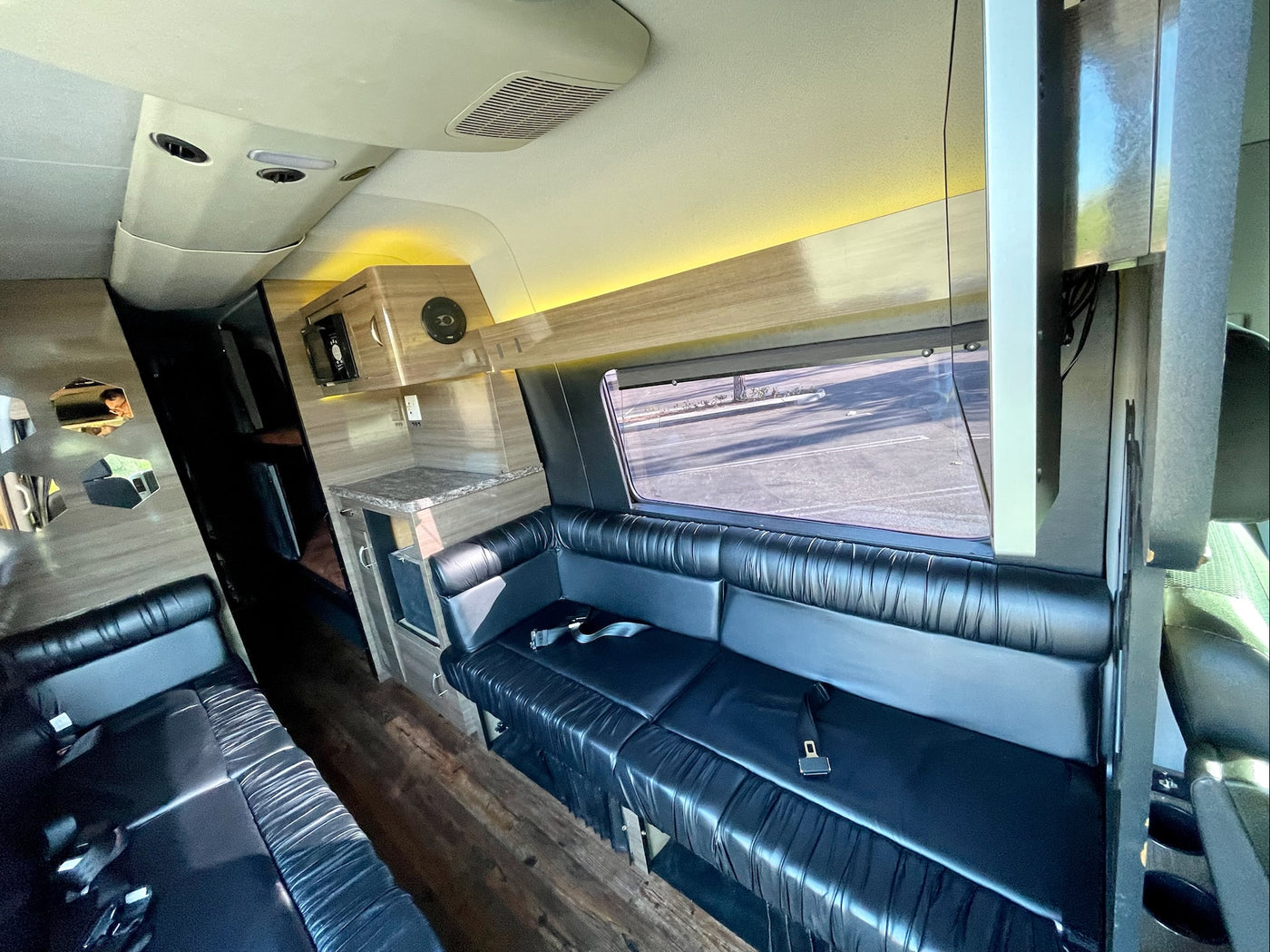 Luxury RV rental interior with spacious black leather seating, a counter area, and warm ambient lighting. — photo 10
