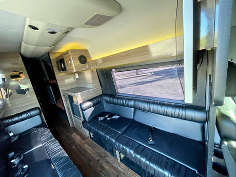 Luxury RV rental interior with spacious black leather seating, a counter area, and warm ambient lighting.