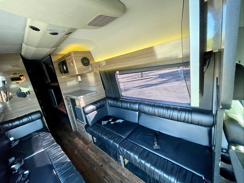 Luxury RV rental interior with spacious black leather seating, a counter area, and warm ambient lighting. — photo 10