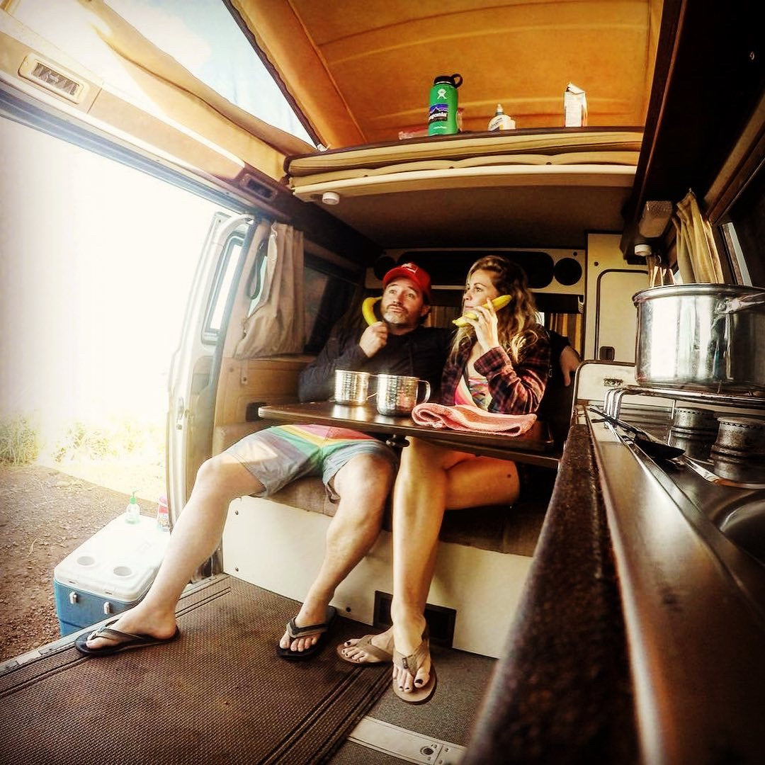 RV rental fun: A couple playfully makes banana calls inside their camper van, enjoying their travel adventure.