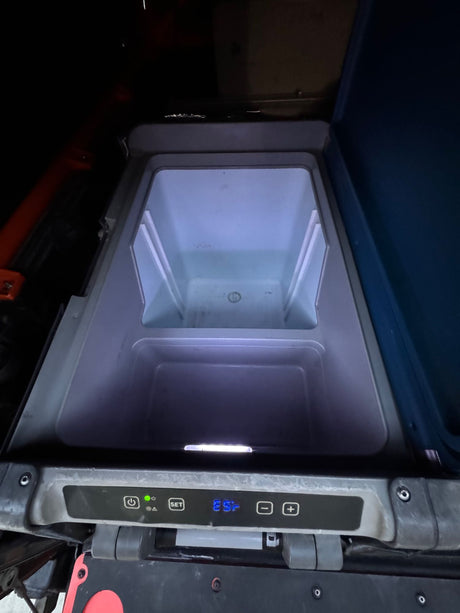 Portable electric cooler in an RV rental, showing its illuminated interior and 25° setting.