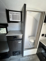 Inside an **rv rental**: a built-in AC, compact kitchen with Dometic fridge, and a wet bath with toilet & shower.